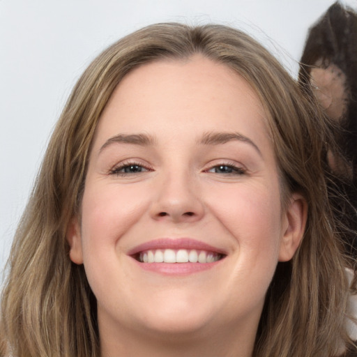 Joyful white young-adult female with long  brown hair and brown eyes