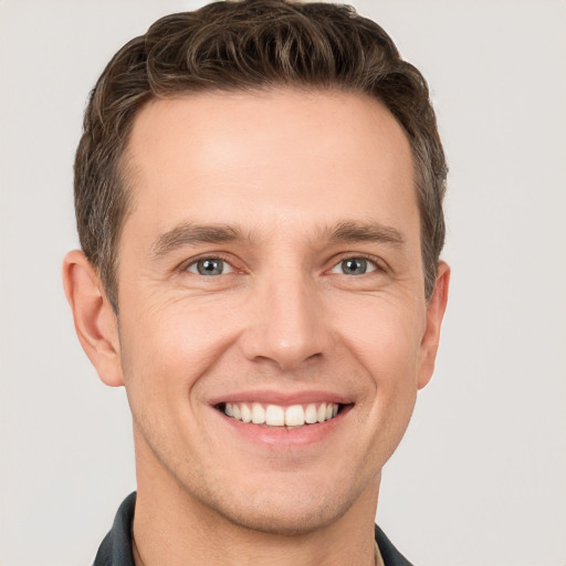 Joyful white young-adult male with short  brown hair and grey eyes