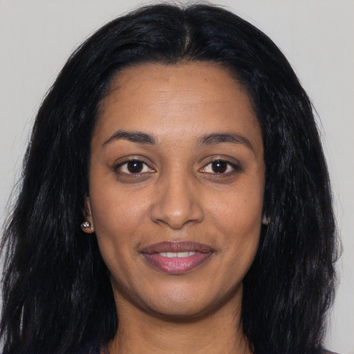 Joyful black young-adult female with long  black hair and brown eyes