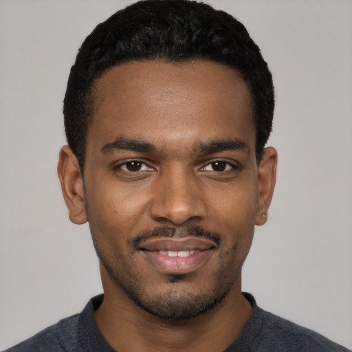 Joyful black young-adult male with short  black hair and brown eyes