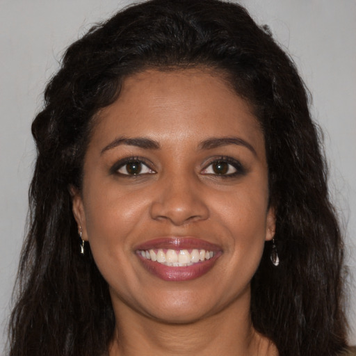 Joyful black young-adult female with long  brown hair and brown eyes