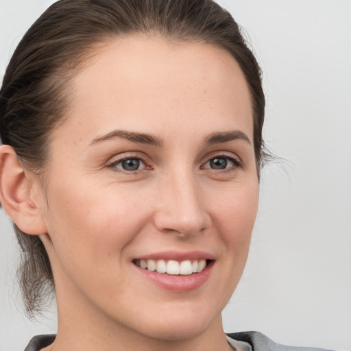 Joyful white young-adult female with medium  brown hair and grey eyes