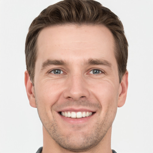 Joyful white young-adult male with short  brown hair and grey eyes