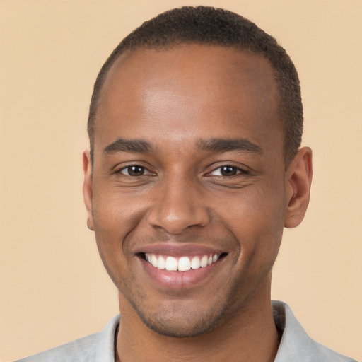 Joyful black young-adult male with short  brown hair and brown eyes