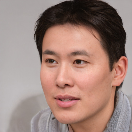 Joyful asian young-adult male with short  brown hair and brown eyes