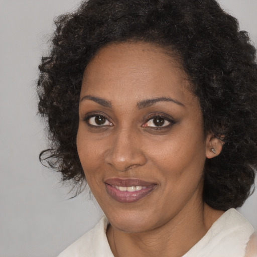 Joyful black adult female with medium  brown hair and brown eyes