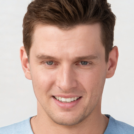 Joyful white young-adult male with short  brown hair and grey eyes