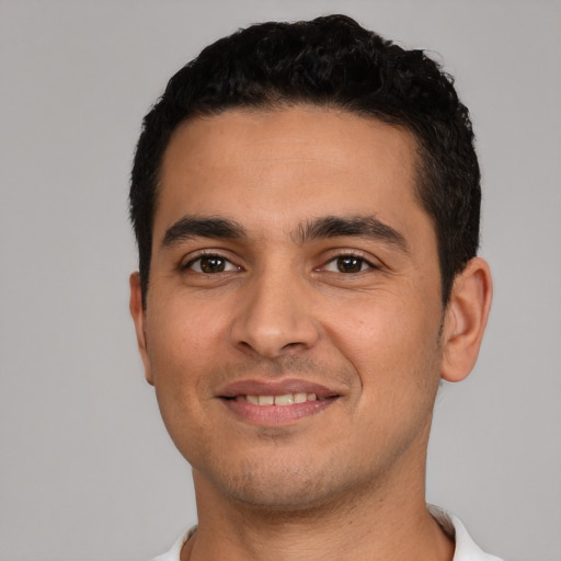 Joyful latino young-adult male with short  black hair and brown eyes