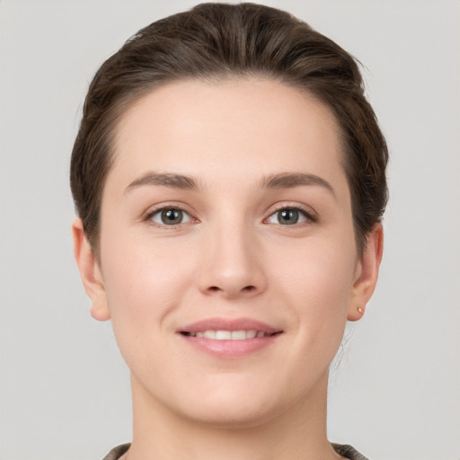 Joyful white young-adult female with short  brown hair and grey eyes