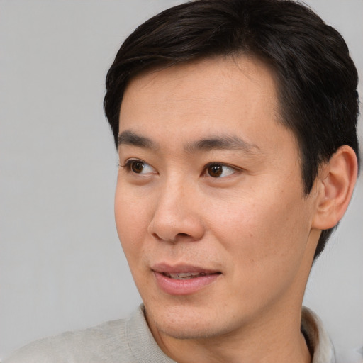 Joyful asian young-adult male with short  brown hair and brown eyes