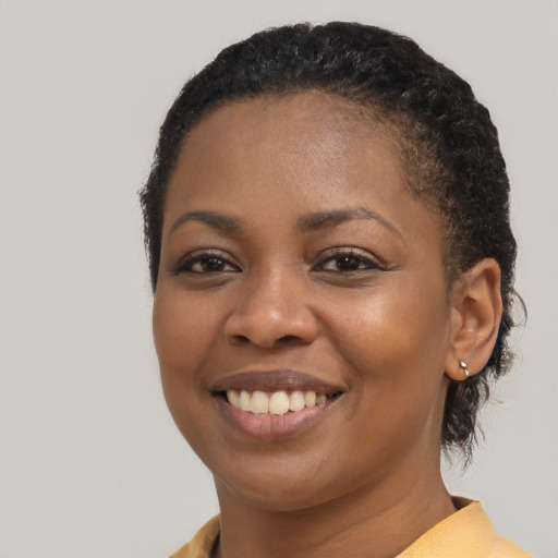 Joyful black young-adult female with short  black hair and brown eyes