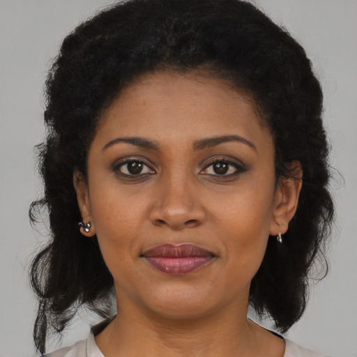 Joyful black young-adult female with long  brown hair and brown eyes