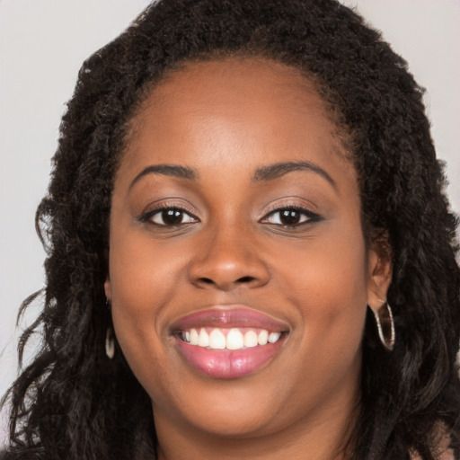 Joyful black young-adult female with long  brown hair and brown eyes