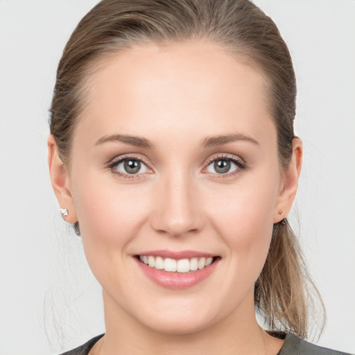 Joyful white young-adult female with medium  brown hair and grey eyes