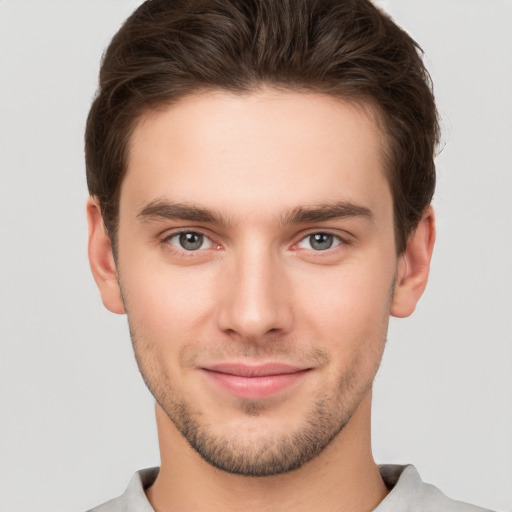 Joyful white young-adult male with short  brown hair and grey eyes