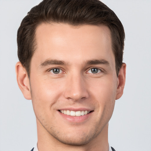 Joyful white young-adult male with short  brown hair and grey eyes