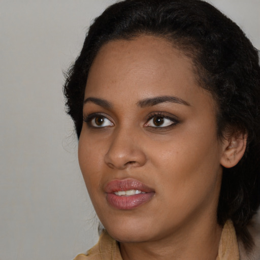 Joyful black young-adult female with long  brown hair and brown eyes