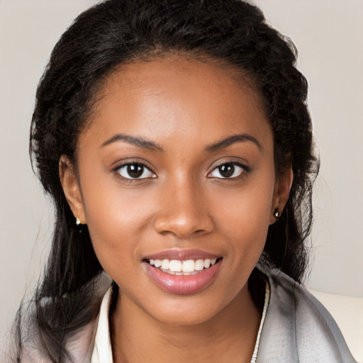 Joyful black young-adult female with long  brown hair and brown eyes