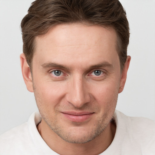 Joyful white young-adult male with short  brown hair and grey eyes