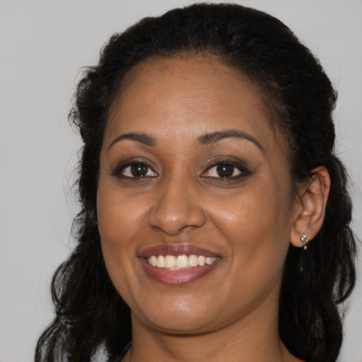 Joyful black young-adult female with long  brown hair and brown eyes