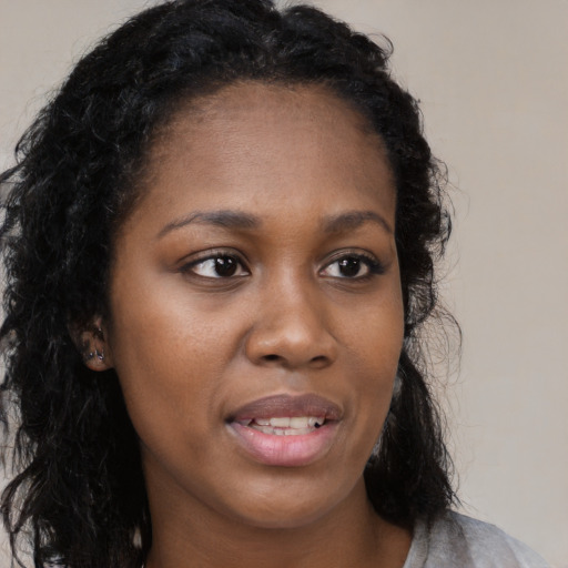 Joyful black young-adult female with long  brown hair and brown eyes