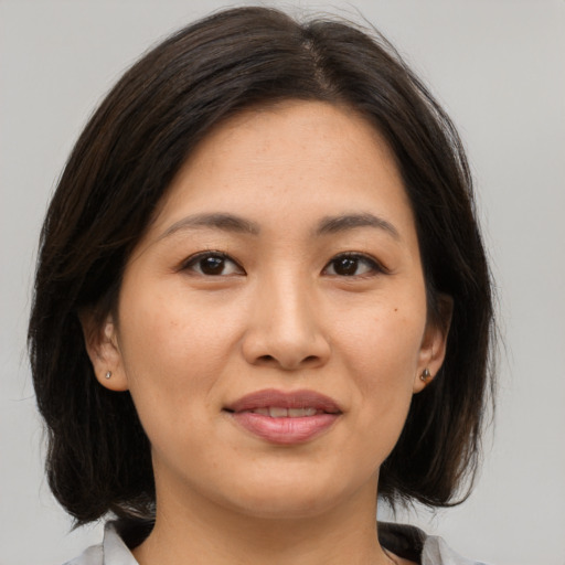 Joyful asian young-adult female with medium  brown hair and brown eyes
