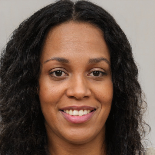 Joyful black young-adult female with long  brown hair and brown eyes