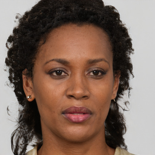 Joyful black adult female with long  brown hair and brown eyes
