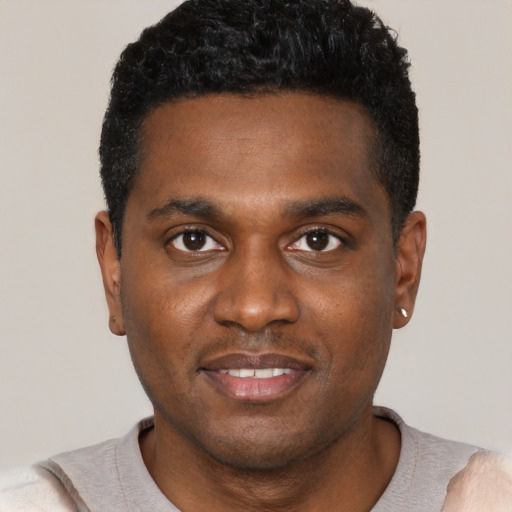 Joyful black young-adult male with short  black hair and brown eyes