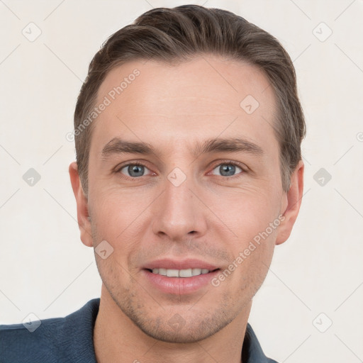 Joyful white young-adult male with short  brown hair and grey eyes