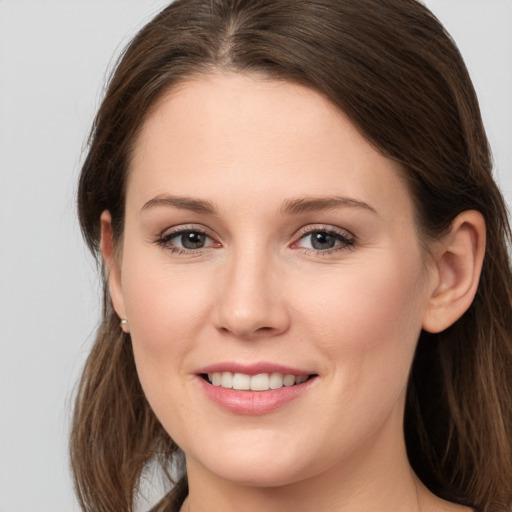 Joyful white young-adult female with long  brown hair and grey eyes