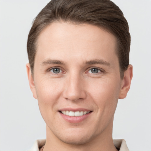 Joyful white young-adult male with short  brown hair and grey eyes