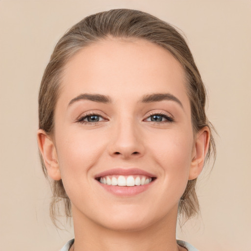 Joyful white young-adult female with medium  brown hair and grey eyes