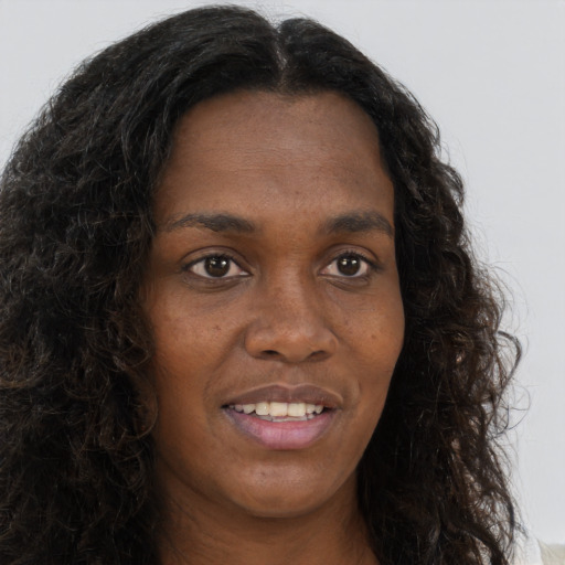 Joyful black young-adult female with long  brown hair and brown eyes