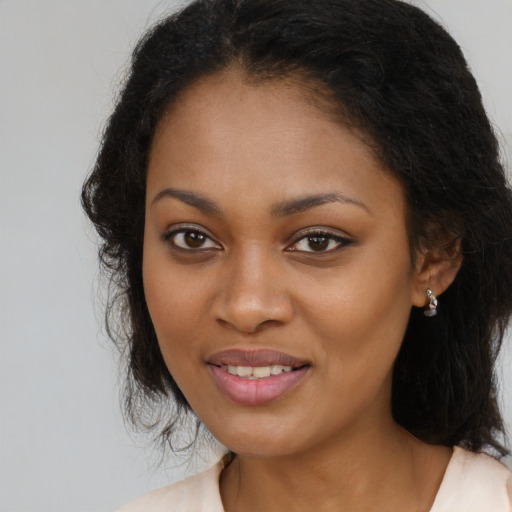 Joyful black young-adult female with long  brown hair and brown eyes