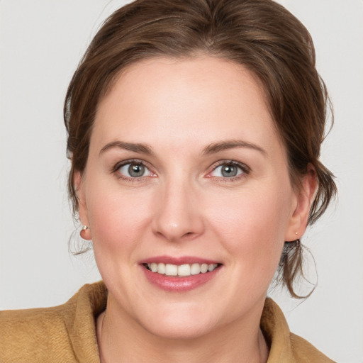 Joyful white young-adult female with medium  brown hair and grey eyes