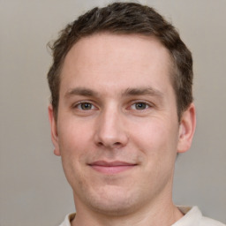 Joyful white young-adult male with short  brown hair and grey eyes