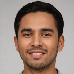 Joyful latino young-adult male with short  black hair and brown eyes