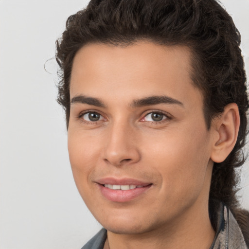 Joyful white young-adult male with long  brown hair and brown eyes