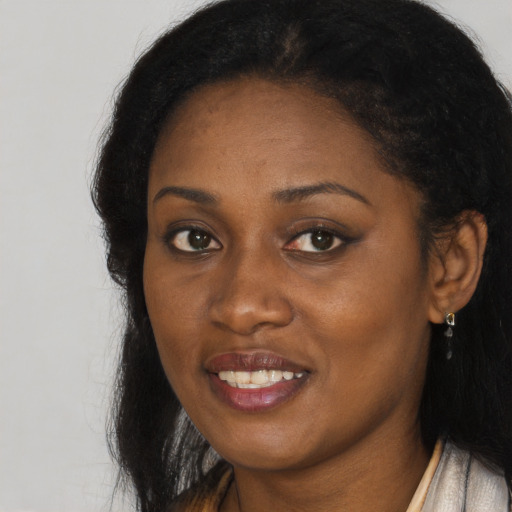 Joyful black young-adult female with long  brown hair and brown eyes