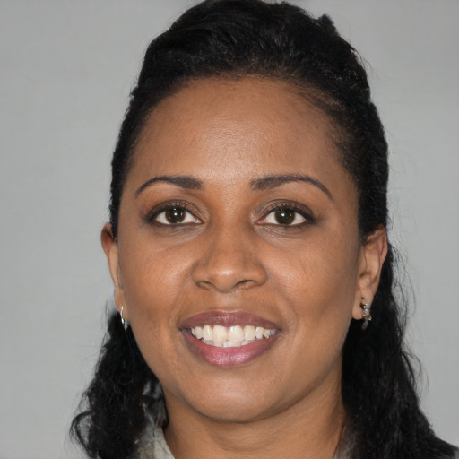 Joyful black young-adult female with long  black hair and brown eyes