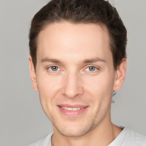 Joyful white young-adult male with short  brown hair and grey eyes