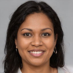 Joyful black young-adult female with long  brown hair and brown eyes