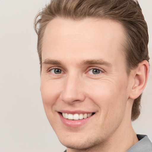 Joyful white young-adult male with short  brown hair and grey eyes