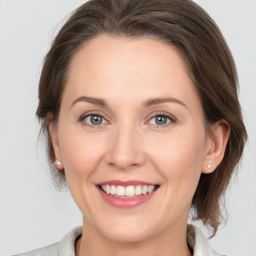 Joyful white young-adult female with medium  brown hair and grey eyes