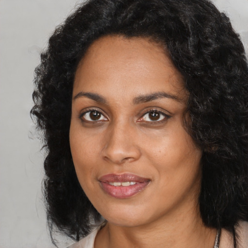 Joyful black young-adult female with long  black hair and brown eyes