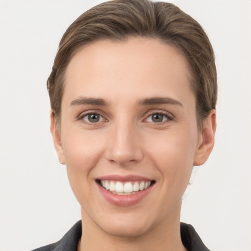 Joyful white young-adult female with short  brown hair and grey eyes