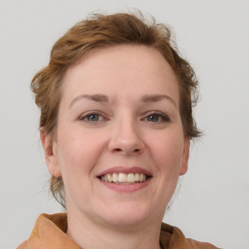 Joyful white young-adult female with medium  brown hair and blue eyes