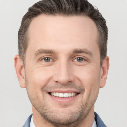 Joyful white young-adult male with short  brown hair and grey eyes