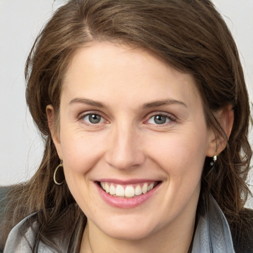 Joyful white young-adult female with long  brown hair and grey eyes